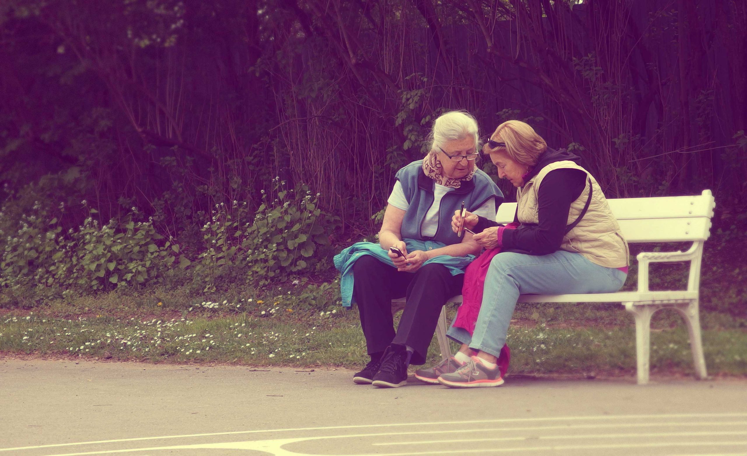 Two retirees sitting on a bench in a park.